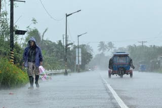 A man walks along a road amid heavy rain due to weather patterns from Super Typhoon Ragasa in Lal-lo town, Cagayan province